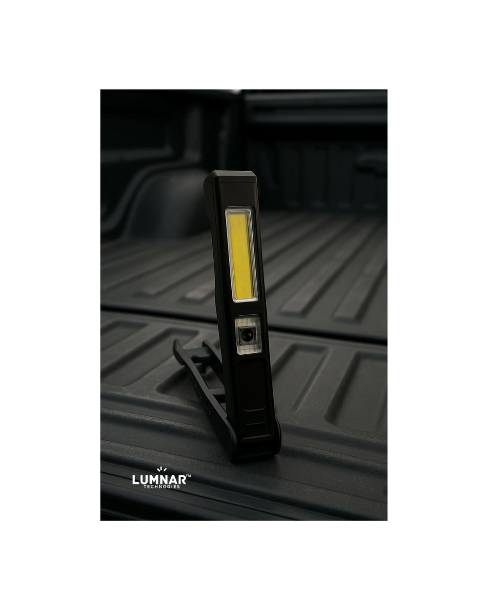 Black LED work light on a black truck bed with Lumnar branding.